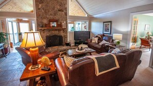 A spacious living room with a stone fireplace, leather furniture, and a television.