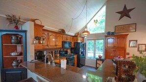 A kitchen with wooden cabinets, granite countertops, a stove, and a large island with stools.