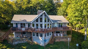 A two-story house with a deck, a staircase, and outdoor seating.