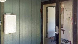 A room with a wooden door, a small window, and a visible bench outside. - 5 Person Holiday Home in Vejby (Vejby)