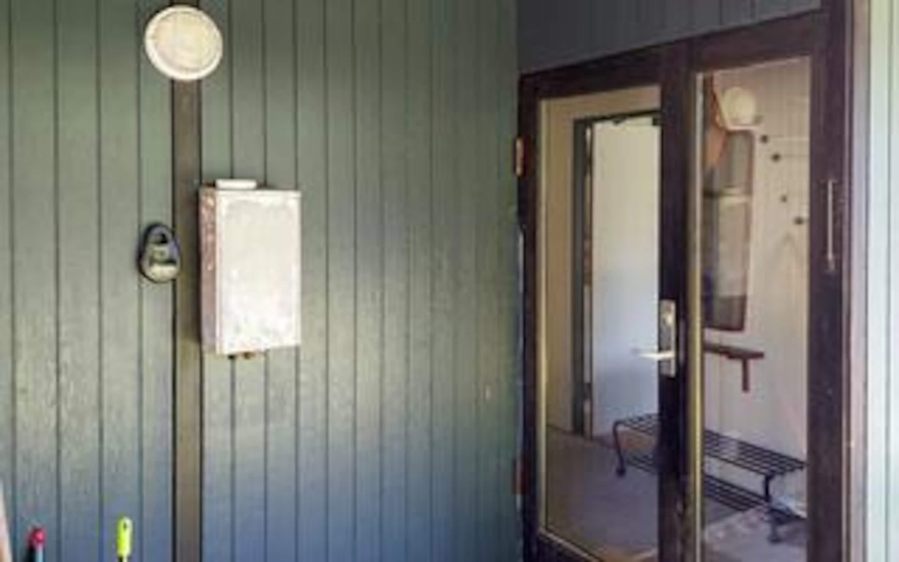 A room with a door, a small window, and a wall-mounted light fixture.