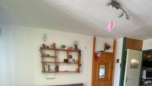 A living room with a grey sofa, wooden shelves, a small table, and a wooden chair.