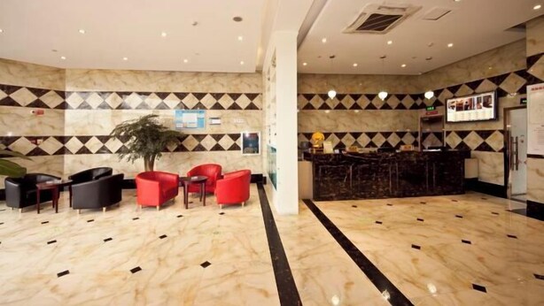 Eine Hotelhalle mit Marmorboden, einer Rezeption und Sitzgelegenheiten.