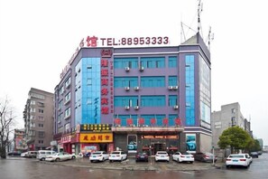 Un immeuble à plusieurs étages, sur lequel on peut voir une grande enseigne rouge bien visible, affichant un numéro de téléphone.
