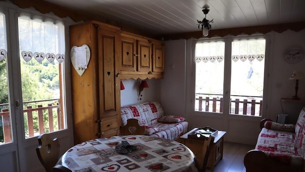 A cozy room with a wooden table, a sofa, and a window with a view of greenery. - 2nd floor, balcony, parking, tv, ski locker, 40m², Valloire (Valloire)