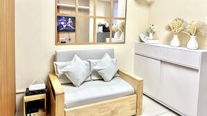 Ein modernes Wohnzimmer mit grauem Sofa, einem Holznachttisch und einem weißen Schrank.