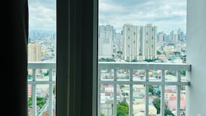 Blick aus einem Fenster mit Metallgeländer auf eine Skyline mit mehreren Hochhäusern.