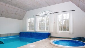 Une piscine intérieure dotée d’un jacuzzi bleu et d’un espace piscine séparé.