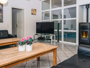 A living room with a TV, a fireplace, and a large window. - 4 Star Holiday Home in Ulfborg (Ulfborg)