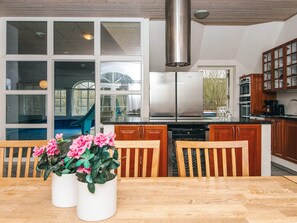Une cuisine moderne dotée d’un grand îlot central, d’appareils électroménagers en acier inoxydable et d’armoires en bois.