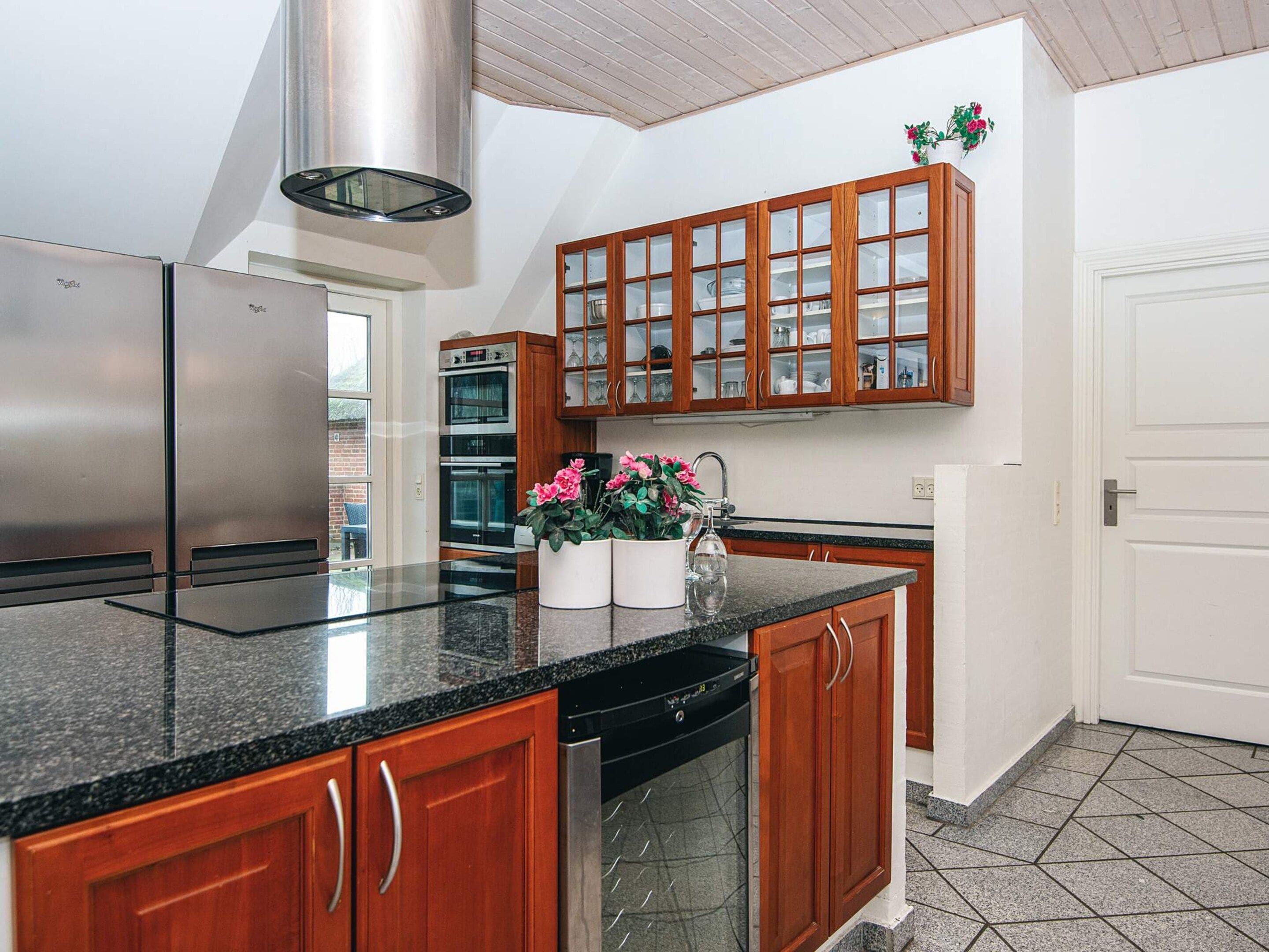A modern kitchen with stainless steel appliances, wooden cabinets, and a granite countertop.