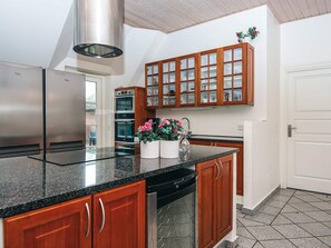 Una cocina moderna con electrodomésticos de acero inoxidable, gabinetes de madera y encimera de granito.