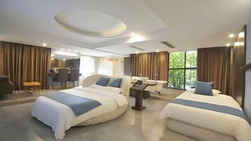A modern hotel room with two beds, a desk, and a view of the outdoors.