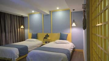 A hotel room with two single beds, a nightstand, a lamp, and a yellow partition wall.