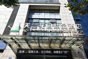 Fachada de un hotel con un gran letrero en inglés y chino, que indica que es el Rong Garden Boutique Hotel.