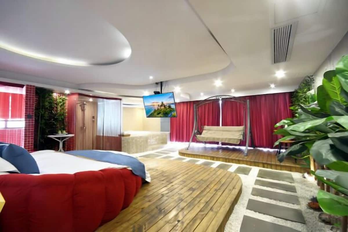 Ein modernes Hotelzimmer mit einem großen Bett, einer Schaukel, einem kleinen Tisch und einem Fernseher.