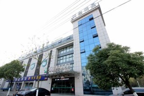 Un edificio de varios pisos con un diseño arquitectónico moderno, que cuenta con una entrada destacada con puertas de vidrio y señalización.