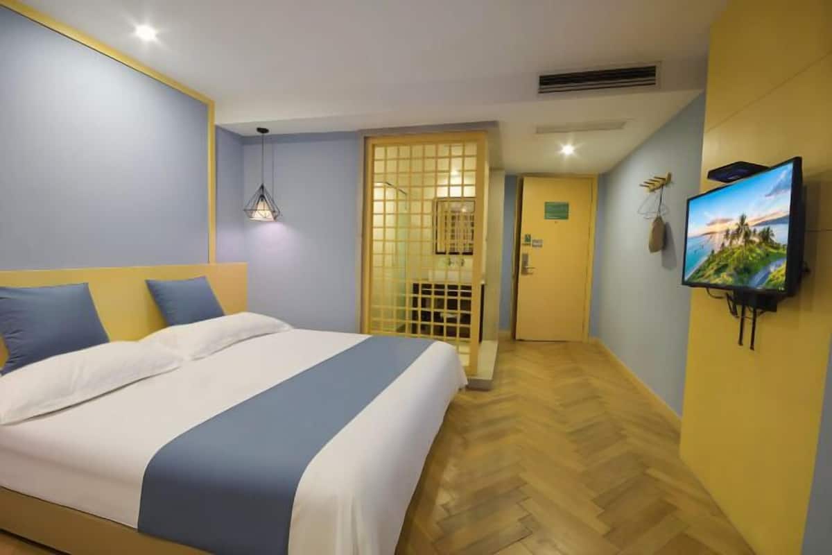 Ein Hotelzimmer mit einem Bett, einem an der Wand befestigten Fernseher und Holzboden.