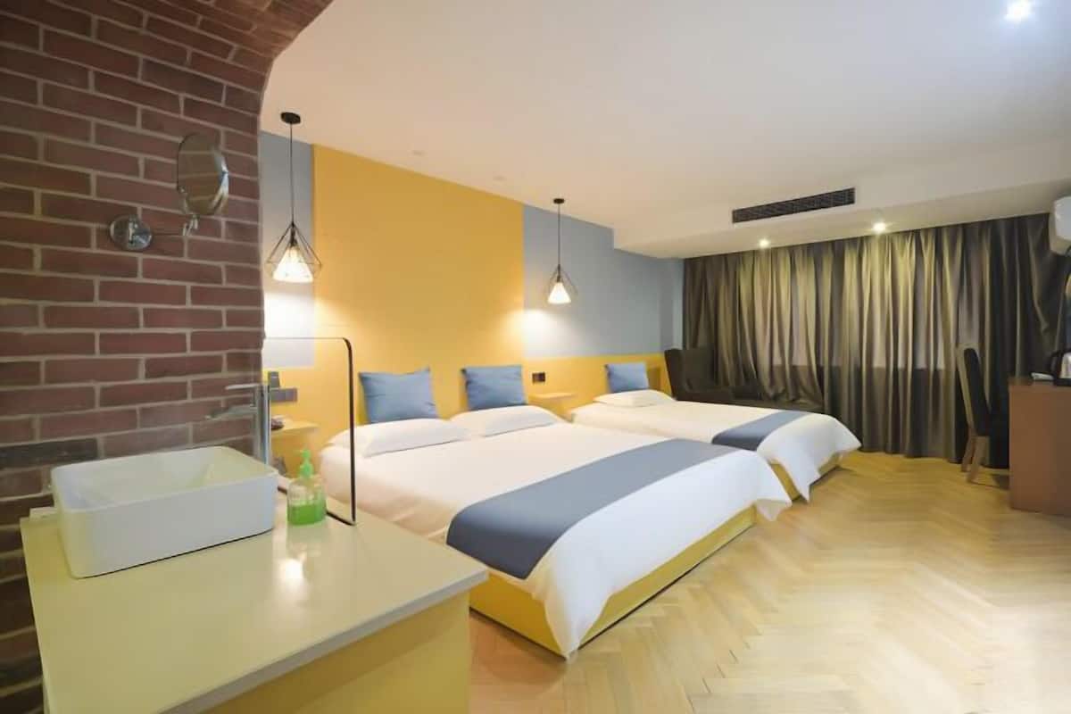 Ein Hotelzimmer mit zwei Betten, einem Badezimmer mit Waschbecken und einer Ziegelwand.