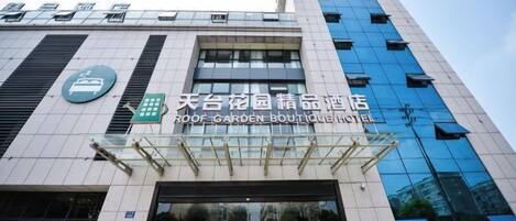 A building with a sign for 'ROOF GARDEN BOUTIQUE HOTEL' and a large glass entrance.