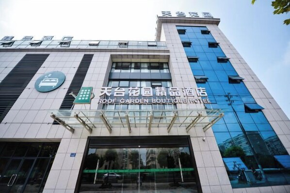 A building with a sign for 'ROOF GARDEN BOUTIQUE HOTEL' and a large glass entrance. - Tiantai Garden Boutique Hotel (Tongxiang)