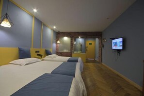 Ein Hotelzimmer mit zwei Betten, einem Fernseher, einer Ziegelwand und einem Holzboden.