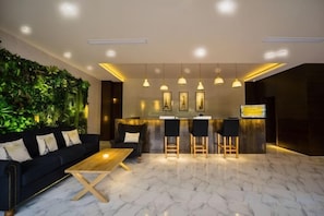 A modern interior with a black sofa, wooden coffee table, and a bar area with stools. - Tiantai Garden Boutique Hotel (Tongxiang)