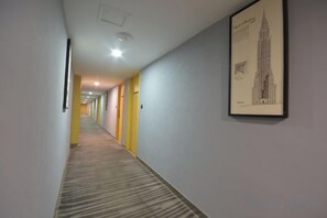 A hallway with a carpeted floor, yellow walls, and a framed picture of a building on the right wall. - Tiantai Garden Boutique Hotel (Tongxiang)
