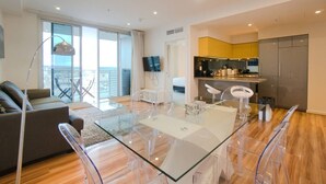 Ein modernes Wohnzimmer mit einem Glastisch, einer Couch und einem Balkon mit Blick.