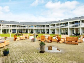 Un patio con muebles de madera y un edificio con varios balcones.