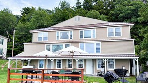 A two-story house with a covered patio area featuring outdoor furniture and umbrellas.