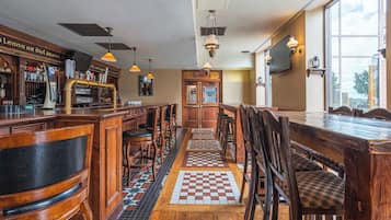 A bar area with wooden furniture, a checkered floor, and a view through large windows.