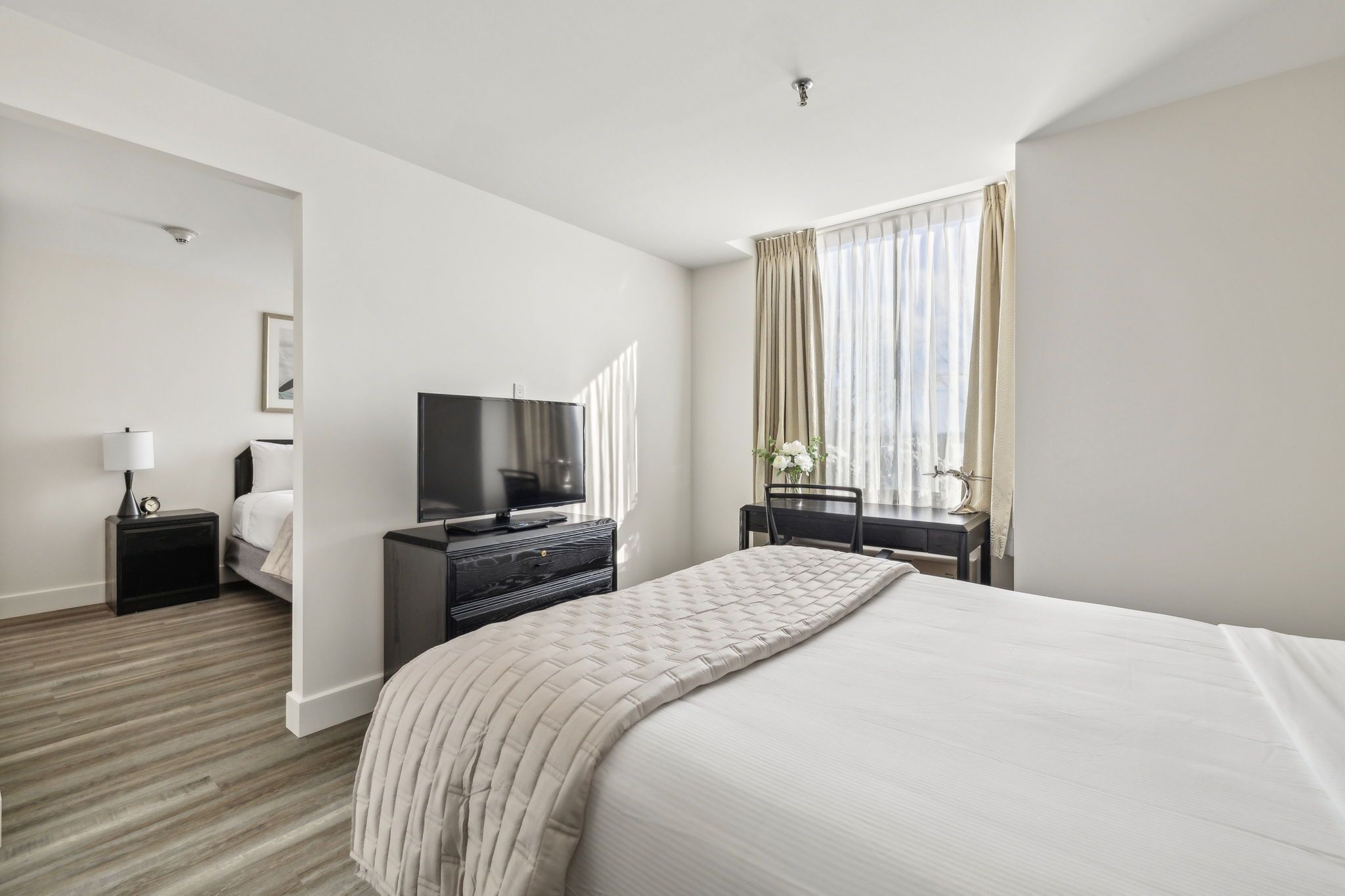 A hotel room with a bed, a TV, a desk, and a chair.