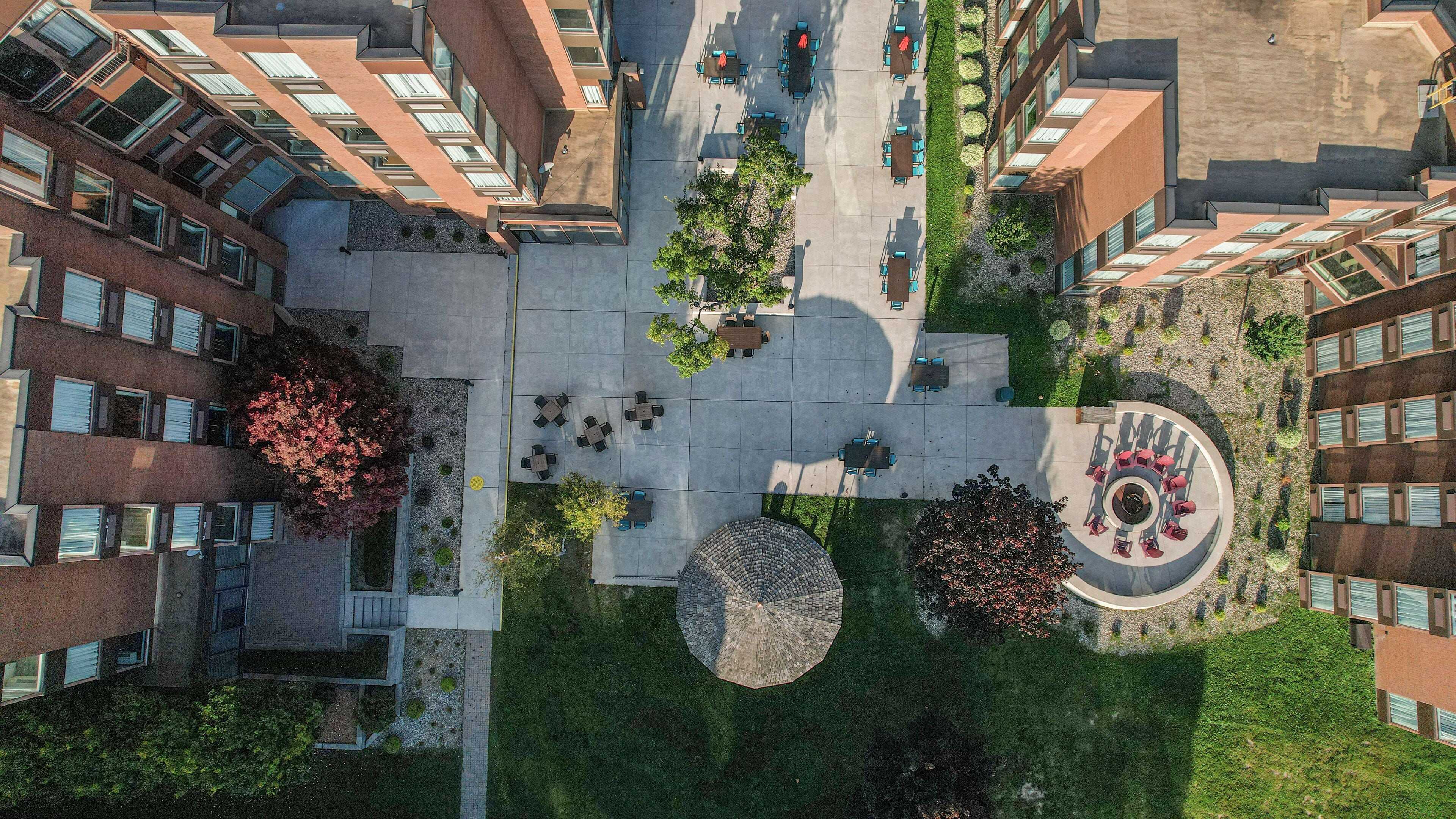 Vue aérienne d’une cour avec des espaces de repos en plein air, un espace de détente circulaire central et une végétation luxuriante tout autour.