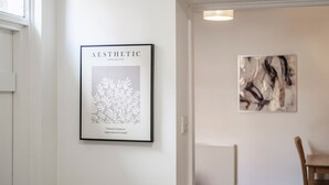 Ein gerahmtes Kunstwerk mit dem Titel 'AESTHETIC', versehen mit einem floralen Muster und einem Zitat, sowie ein weiteres abstraktes Gemälde an der Wand.