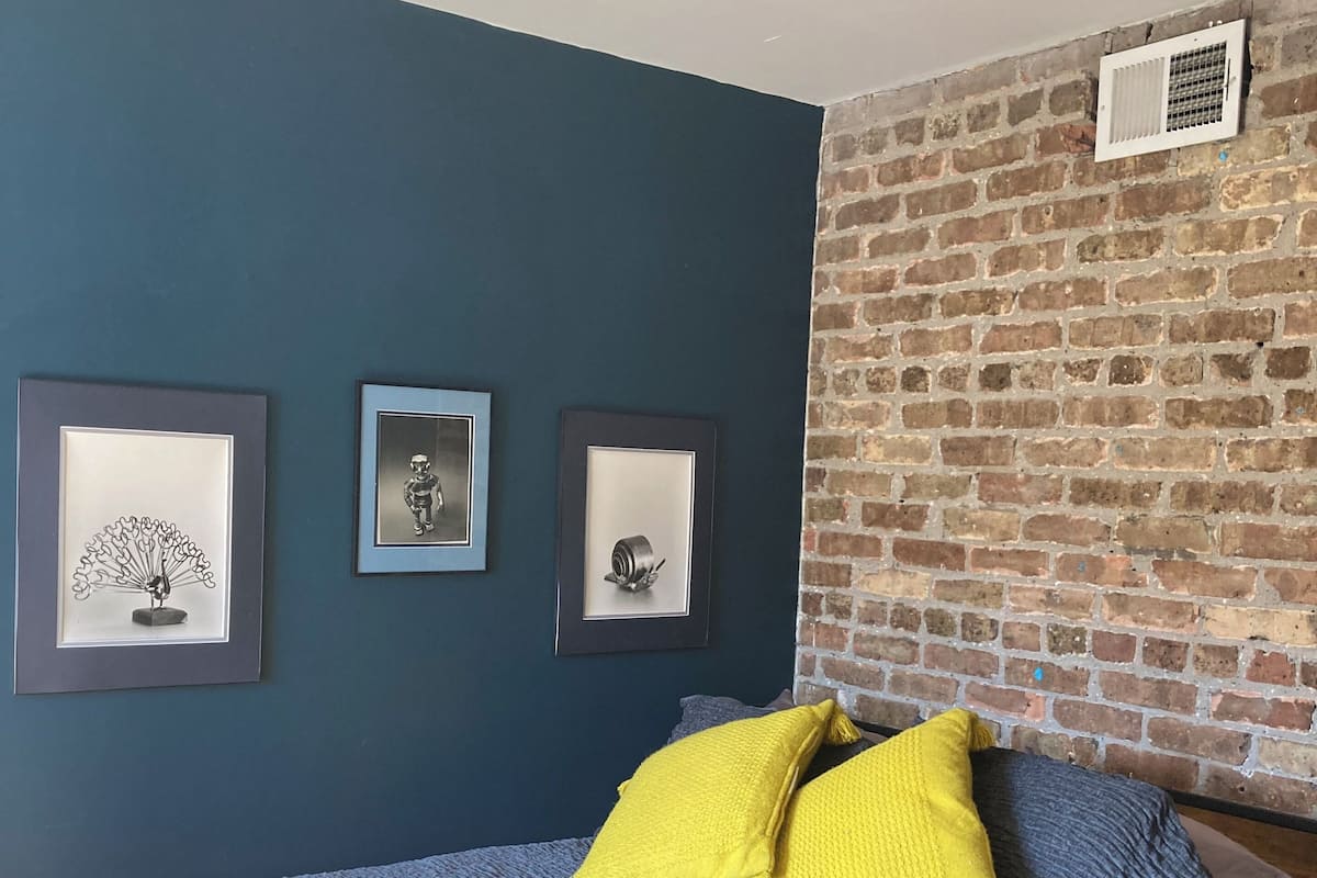 A bedroom with a bed, a ceiling fan, and three framed pictures on the wall.