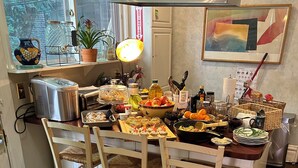 A kitchen with a dining table set for a meal, a dog sitting at the table, and various kitchen appliances and utensils. - Dorothy's (Chicago)