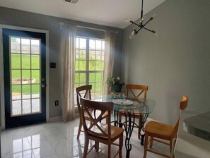 Un espace repas avec une table en verre, des chaises en bois et un luminaire suspendu au plafond.