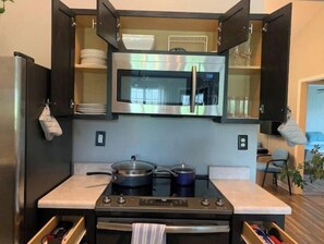 Une cuisine compacte équipée d’un four à micro-ondes, d’un four traditionnel et d’une cuisinière à gaz.