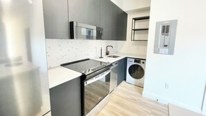 Una cocina moderna con refrigerador de acero inoxidable, microondas, horno y lavadora.