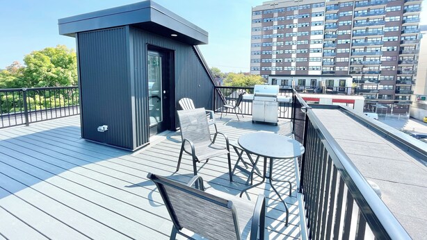 Una terraza en la azotea con una pequeña estructura negra, una parrilla y mobiliario para exteriores.