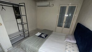 A bedroom with a bed, a wardrobe, a window with shutters, and an air conditioning unit. - Vintage Rooftop (Heliopolis)