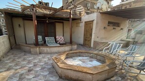 A rooftop patio with a stone-tiled floor, a hot tub, and outdoor seating. - Vintage Rooftop (Heliopolis)