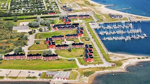 An aerial view of a coastal residential area with a marina, houses, and a road.