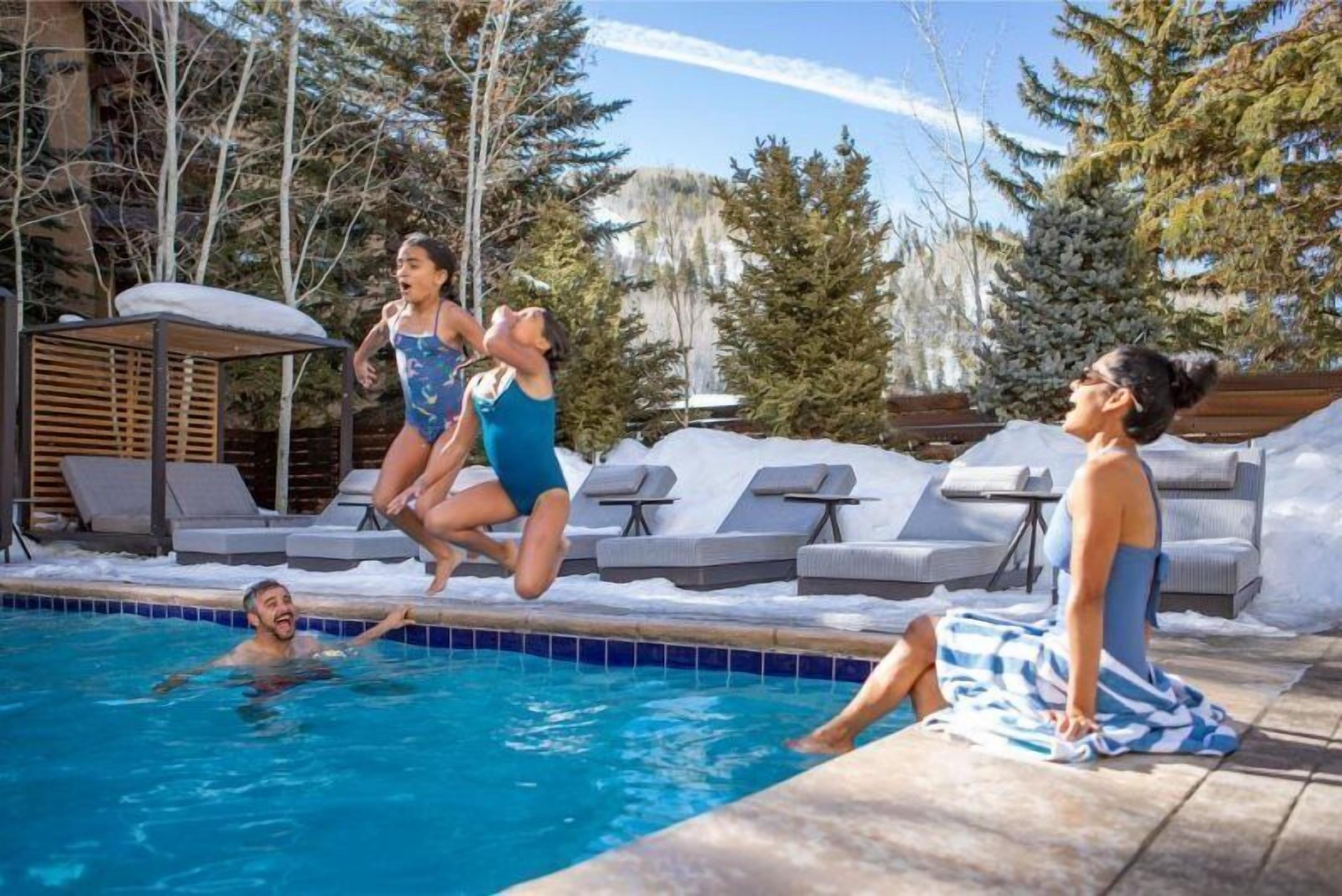 Une piscine dotée de chaises longues et d’un espace salon abrité.