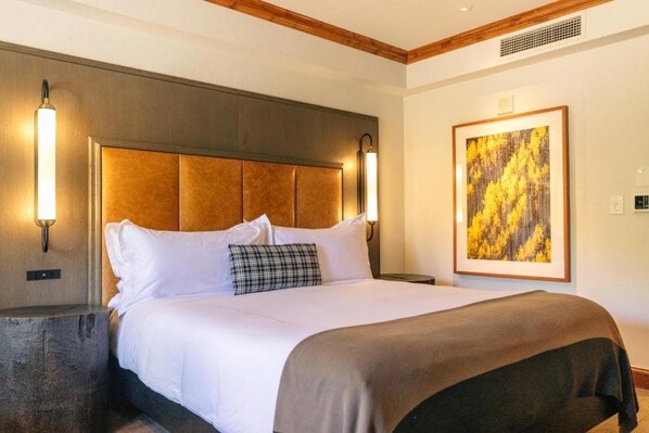 Ein Hotelzimmer mit einem großen Bett, zwei Wandlampen, einem gerahmten Gemälde und einem Holzkopfteil.