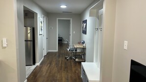 A hallway with a wooden floor, a kitchen area with a refrigerator, a dining table with chairs, and a globe on the table. - Cozy 1-bedroom in charming Durham (Durham)