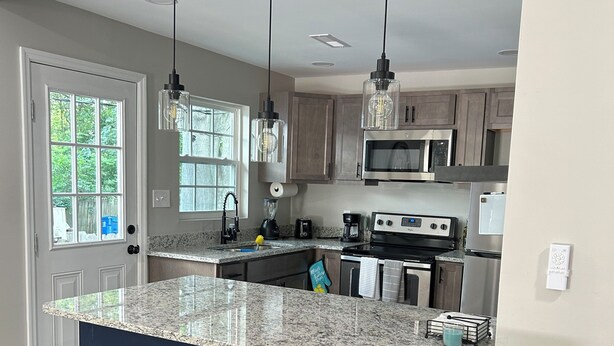 A kitchen with a granite countertop, stainless steel appliances, and a blue accent wall. - Cozy 1-bedroom in charming Durham (Durham)