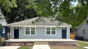 A single-story house with a front porch, two front doors, and a small front yard with a sidewalk leading to the entrance. - Cozy 1-bedroom in charming Durham (Durham)