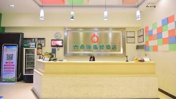 A reception desk with a digital screen, a clock, and a colorful wall decoration.